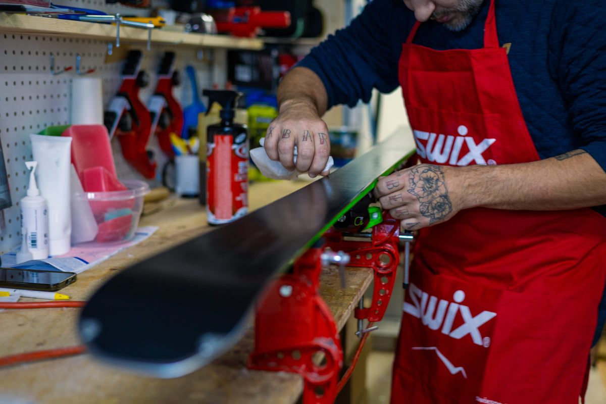 Ski technician waxing a ski on the tuning bench