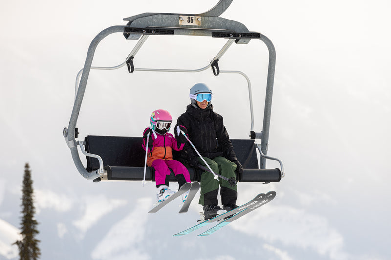 Parent and child riding a chairlift on skis